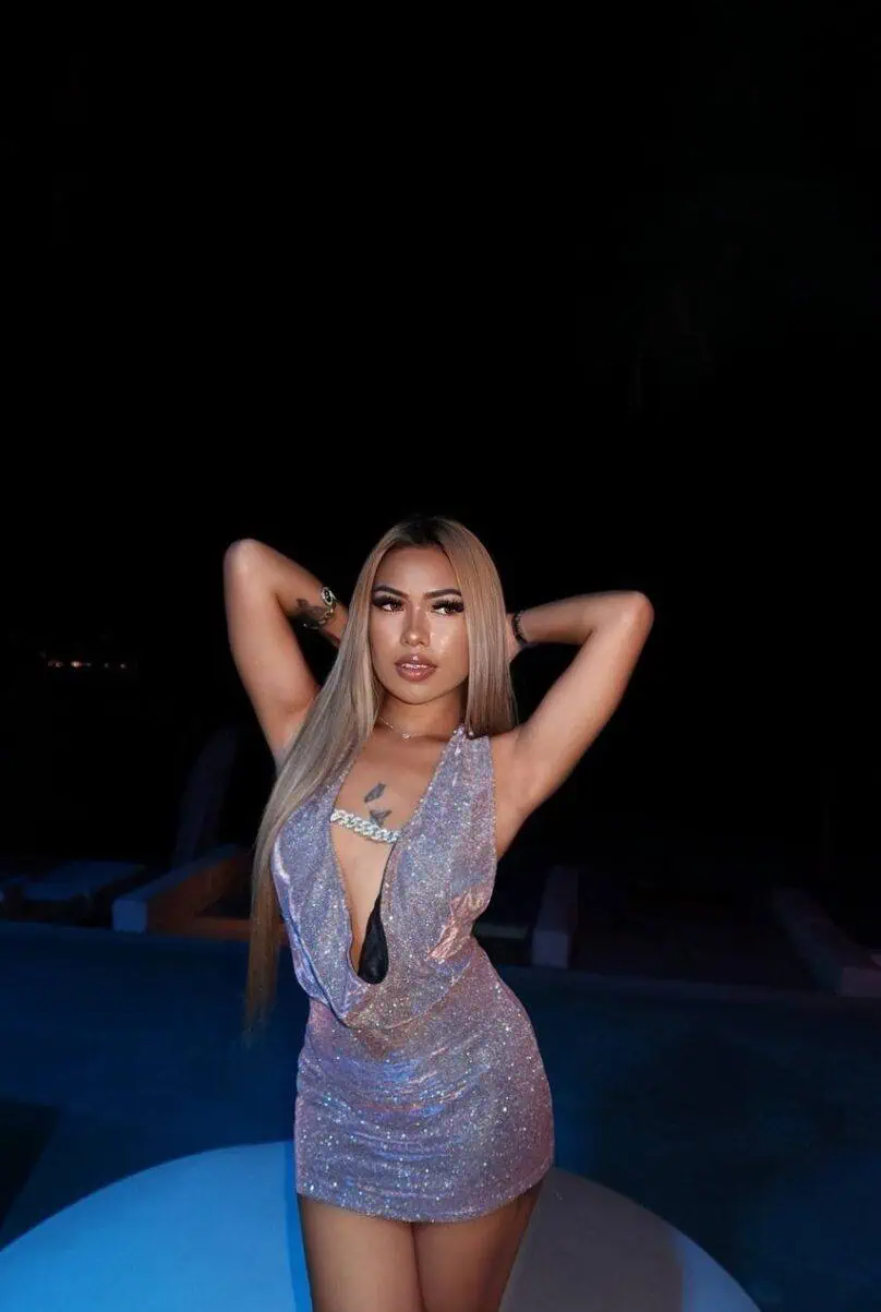 Elegant woman with long blonde hair in a shimmering dress at night, luxury escort in London.